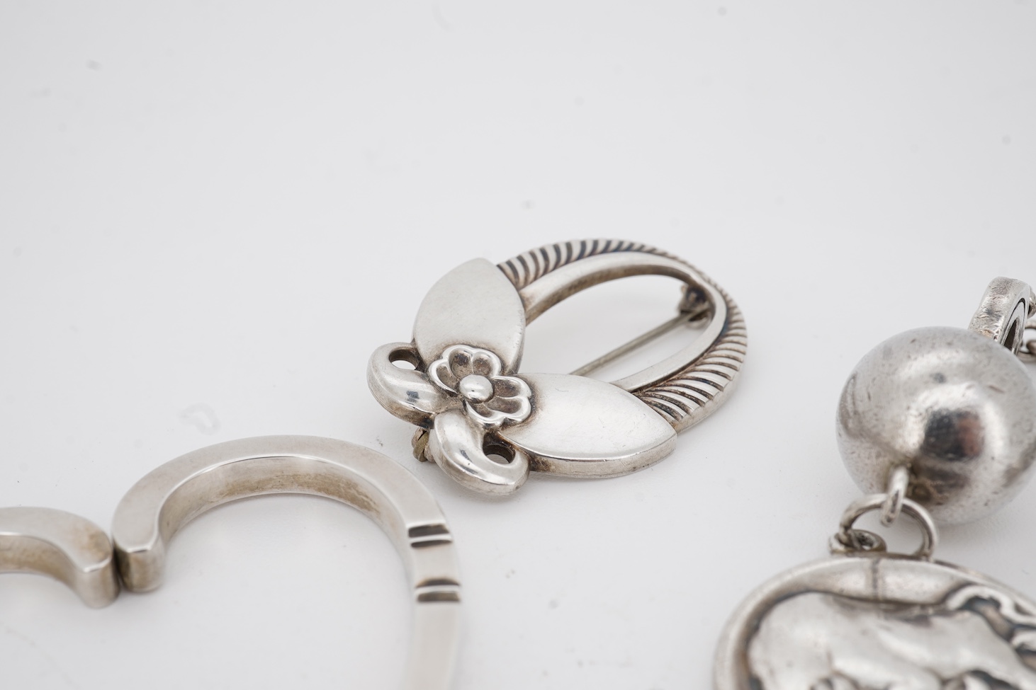 A Danish Georg Jensen sterling twin dolphin brooch, 40mm and a similar flower brooch, design numbers 317 and 227, a 1960's Georg Jensen silver bracelet, design no.46 and a similar 1970's silver heart pendant, design no.4